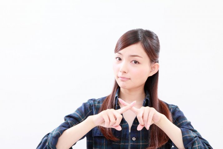 A woman making an "X" with her hands