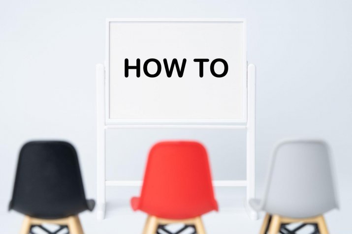 The words "HOWTO" written on a whiteboard and a chair